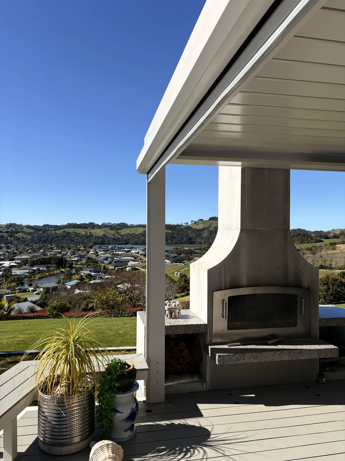 Canvas Cloth Executive screen retracted into its headbox above a covered deck, outdoor fireplace and estuary view beyond