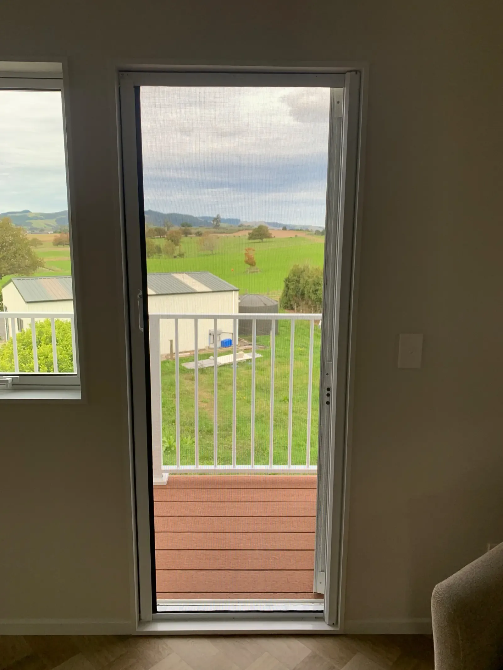MeshLock screen on a sitting-room doorway, balcony rail and Te Kauwhata farmland beyond