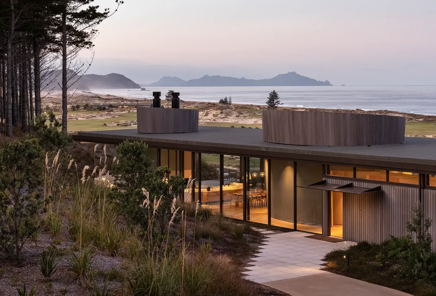 A cedar-clad home at Tara Iti, Te Arai in Northland, dusk light over the links and the sea