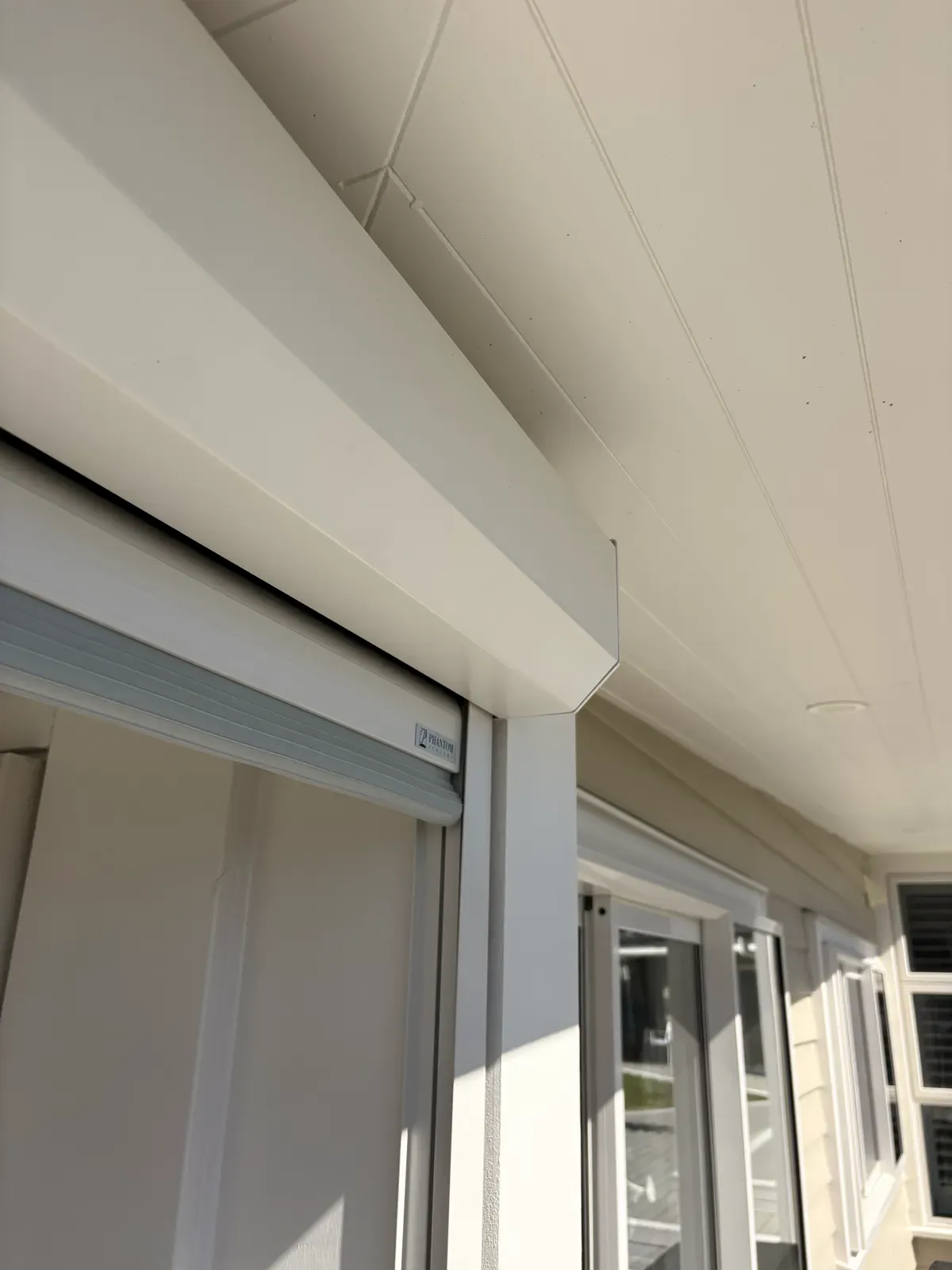 Canvas Cloth Executive headbox running along a lined soffit into a post, with the Phantom badge on the guide track