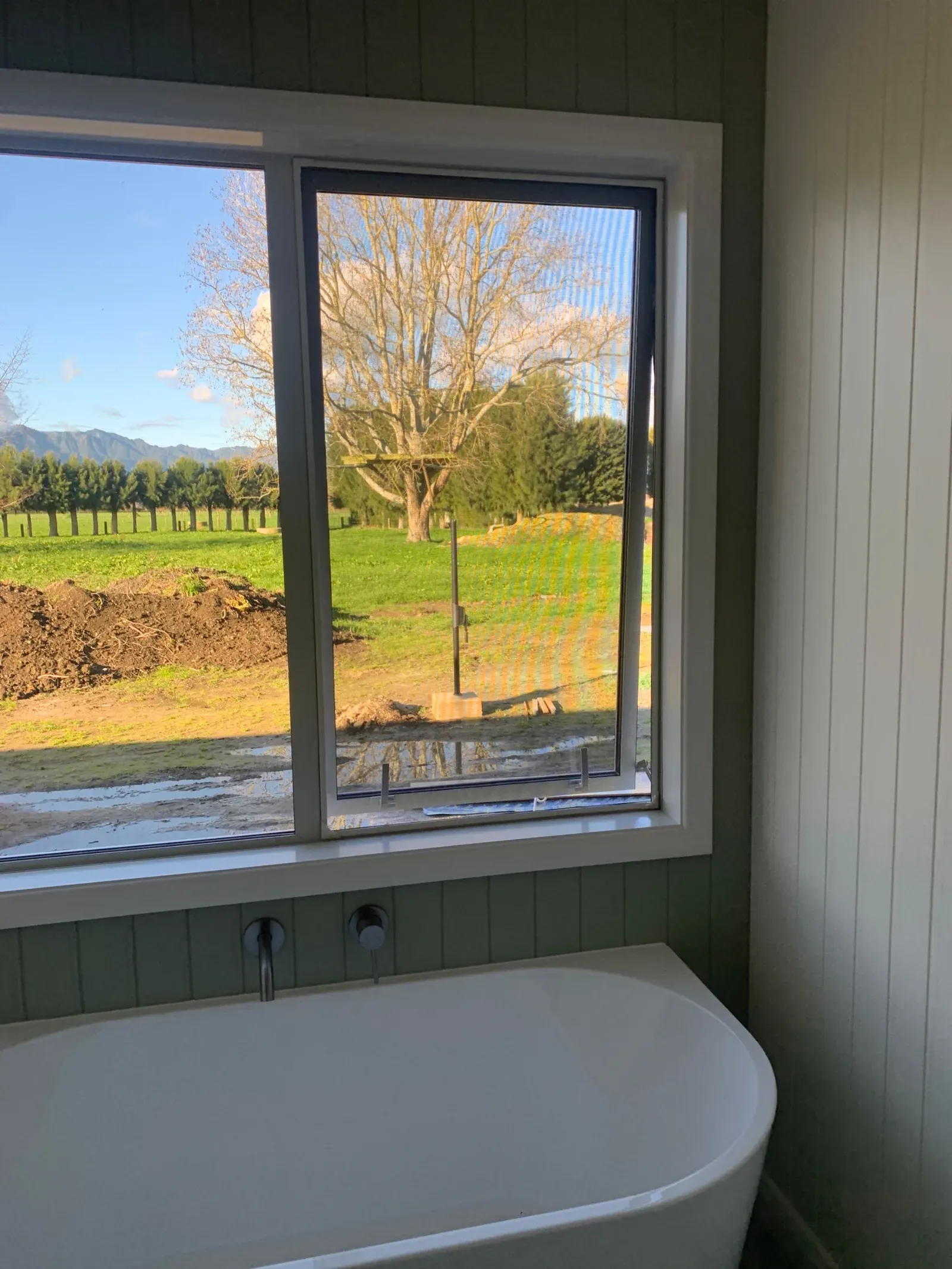 A magnetic window insect screen above a freestanding bath, looking out over farmland