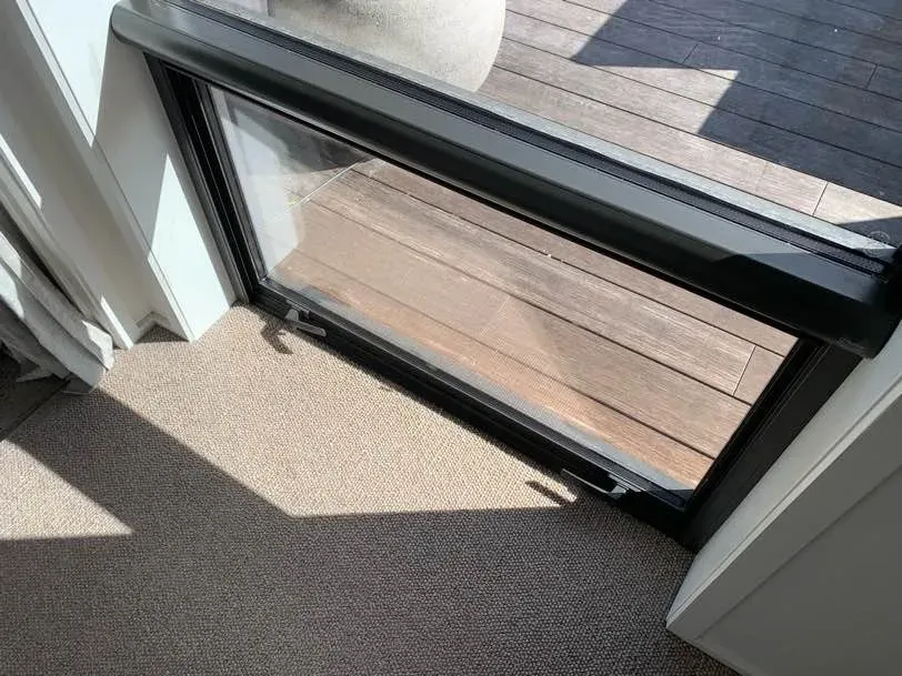 Black Serene retractable screen drawn down over a low awning window opening onto a timber deck