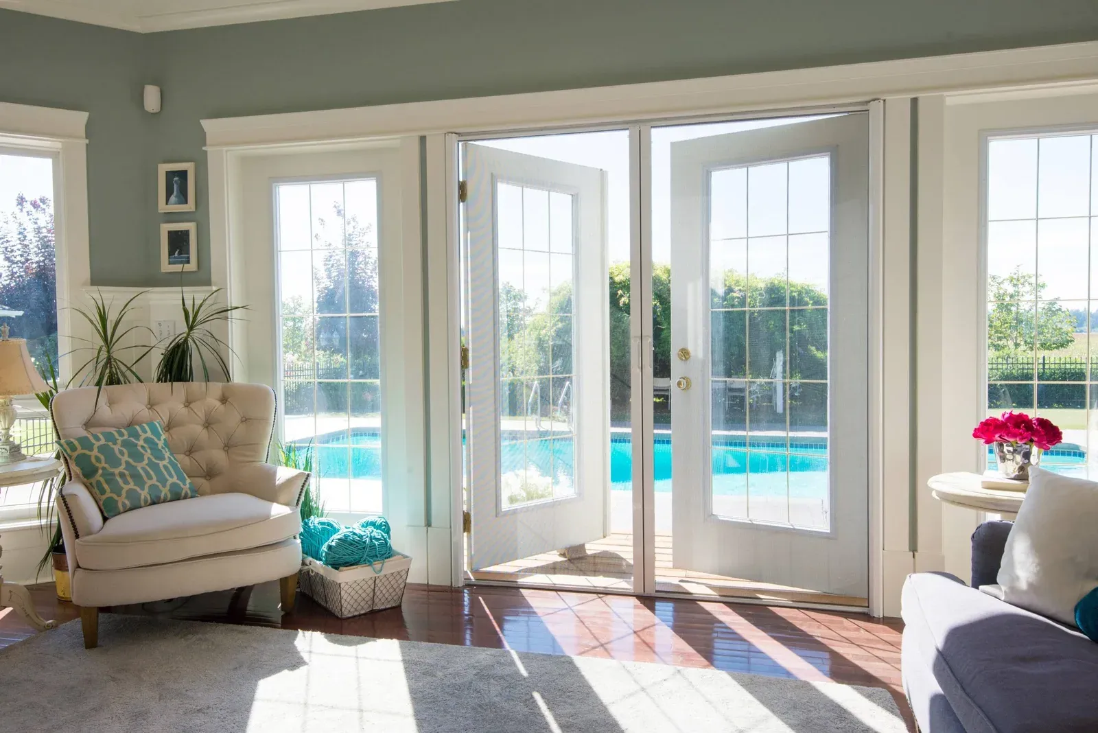 Two retractable insect screens drawn across a pair of French doors, meeting in the middle of the opening, pool beyond
