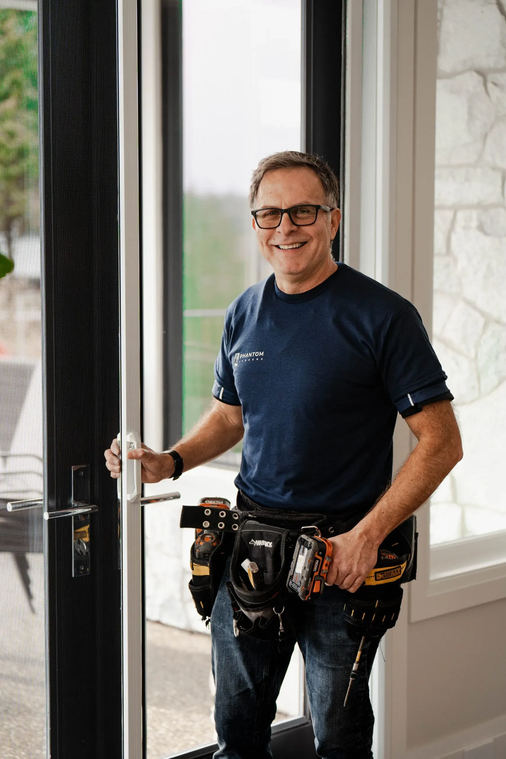 A Phantom Screens installer beside a retractable door screen they have just fitted