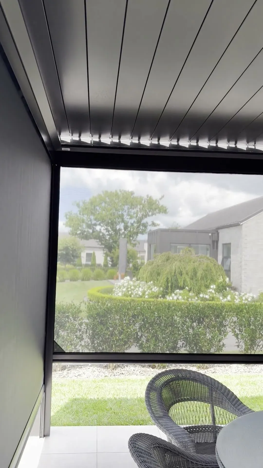 An Executive screen enclosing a louvre-roofed outdoor room, garden beyond the mesh