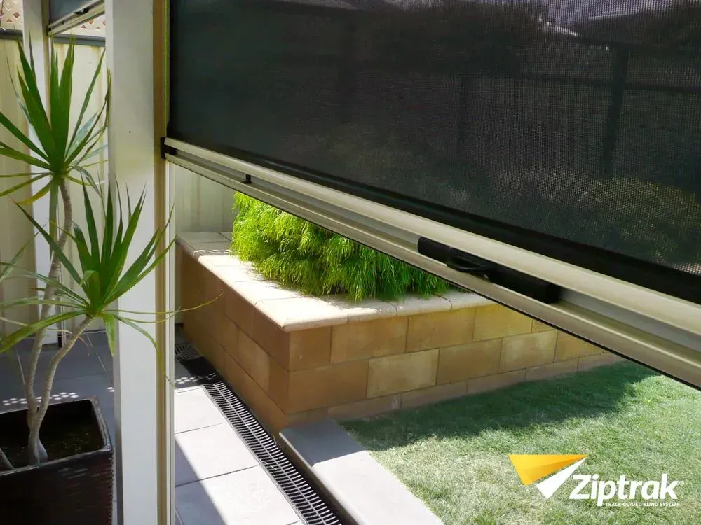 A Ziptrak zip-track outdoor blind drawn down beside a patio